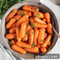 Air fried roasted baby carrots in a gray serving bowl with a serving spoon.