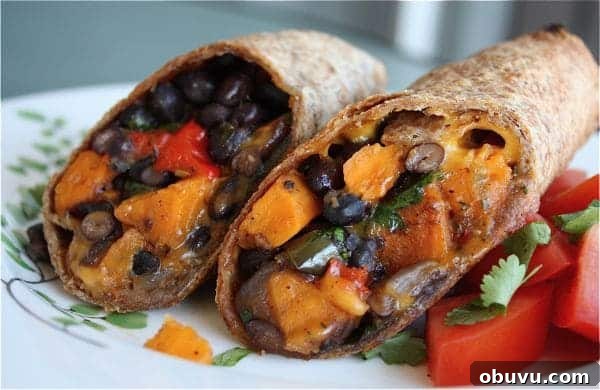 Savory sweet Roasted Veggie and Black Bean Burritos are a delicious vegetarian meal even meat lovers will enjoy! two halves of sweet potato and black bean burrito on a plate
