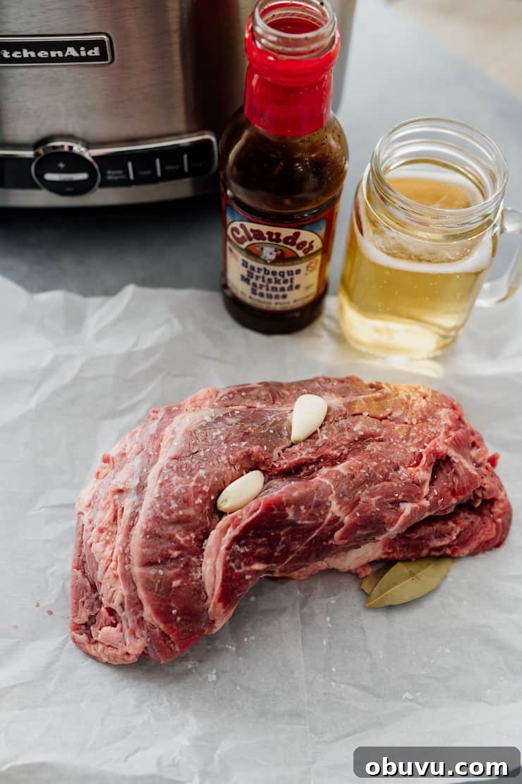 Brisket Sopes: Authentic Mexican Sopes de Carne Deshebrada 3 raw beef brisket on a piece of parchment in front of a slow cooker with a jar of claude's marinade and a glass of beer.