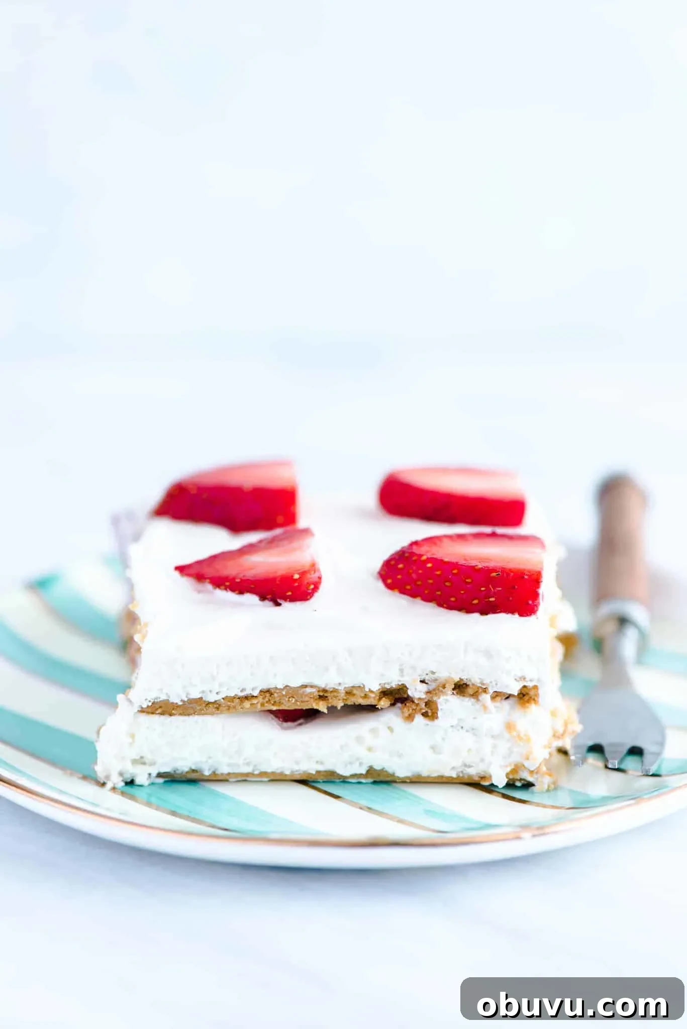 Gluten-Free Strawberry Icebox Cake Recipe for Summer Slices 6 A slice of gluten free strawberry icebox cake on a green and white striped plate