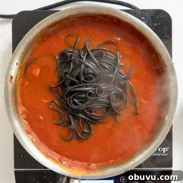 Black Squid Ink Pasta with Tender Calamari and Garlic Wine Sauce 9 Adding squid ink pasta simmering with sauce and calamari.