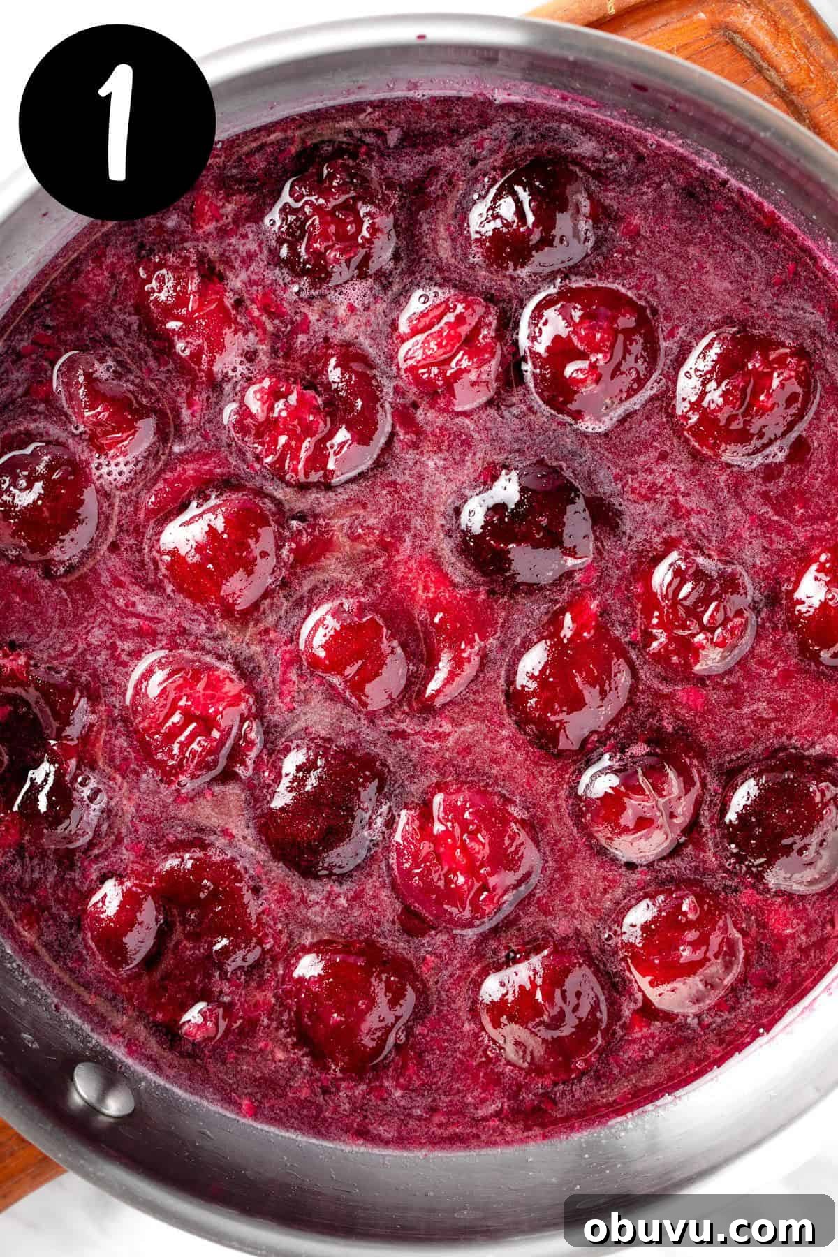 Heating the black cherries, sugar and water together in a saucepan.
