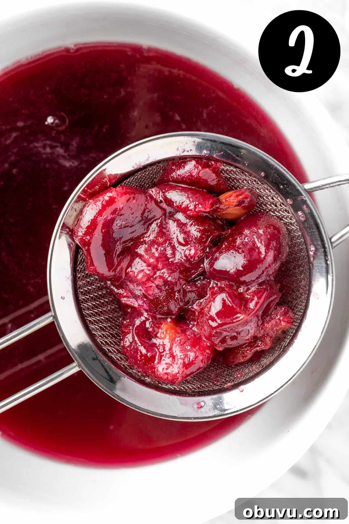 Straining out the cherry pieces from the black cherry syrup.