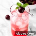 A black cherry mojito garnished with a cherry and mint leaves.