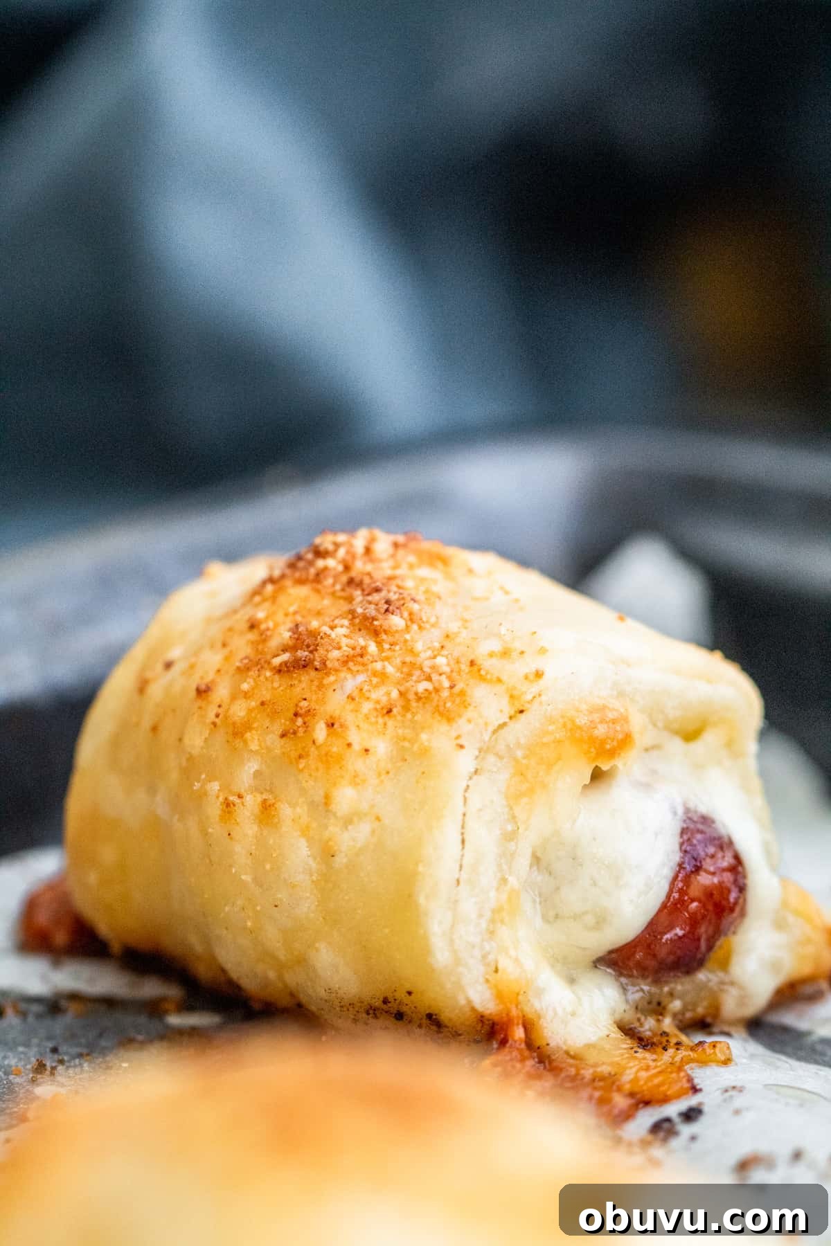 Cheesy Puff Pastry Pigs in a Blanket Recipe 2 Close up show of pigs in a blanket with parchment paper.