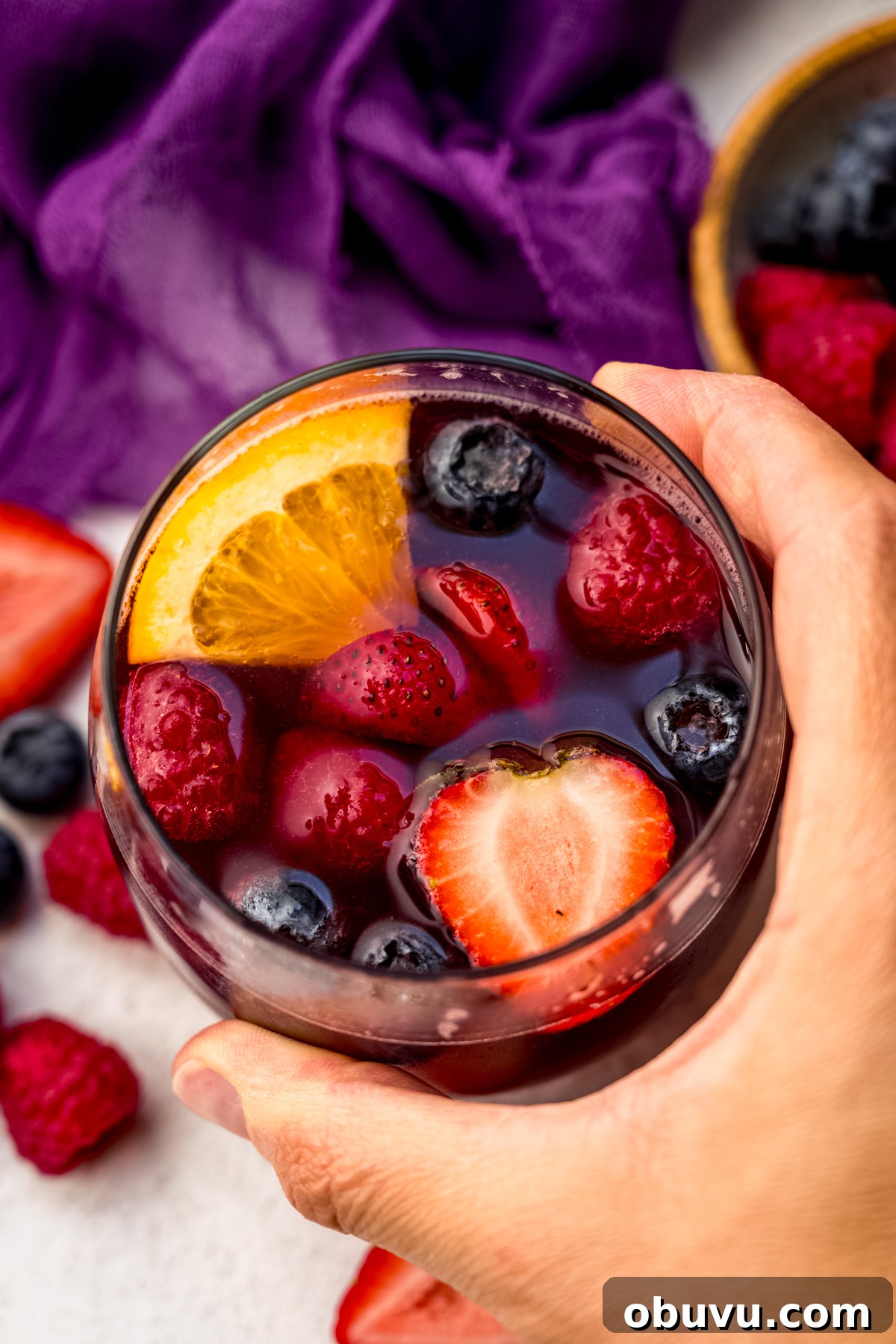 Berry Sangria and Berry Mocktail Recipes for Every Occasion 2 Aerial photo of someone's hand around a glass of berry sangria.