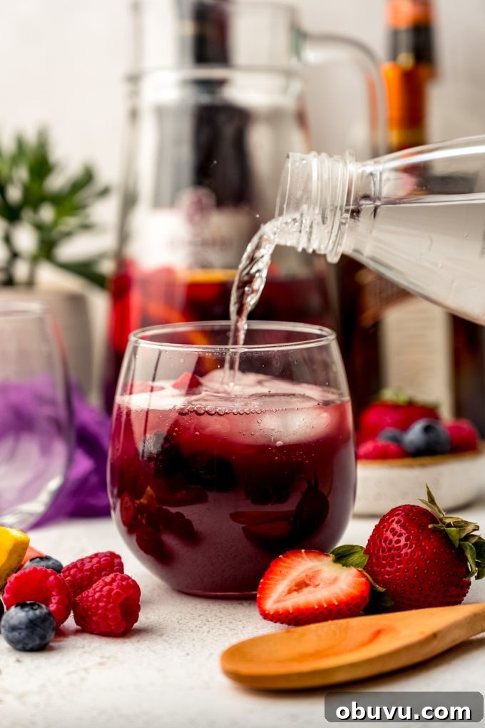 Berry Sangria and Berry Mocktail Recipes for Every Occasion 14 Someone is pouring seltzer water into a glass of berry sangria.