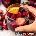Berry Sangria and Berry Mocktail Recipes for Every Occasion 19 Someone's hand around a glass of berry sangria.