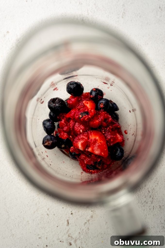 Berry Sangria and Berry Mocktail Recipes for Every Occasion 8 Macerated blueberries, strawberries, and raspberries in the bottom of a glass pitcher.