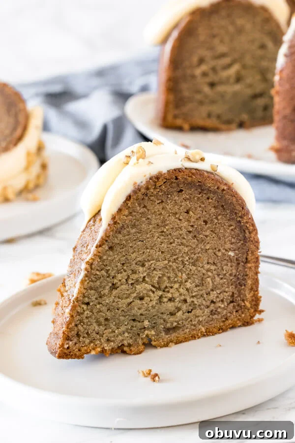 Moist Banana Bundt Cake Recipe for Perfectly Tender Loaf 2 A slice of banana bundt cake with cream cheese frosting on a white plate.