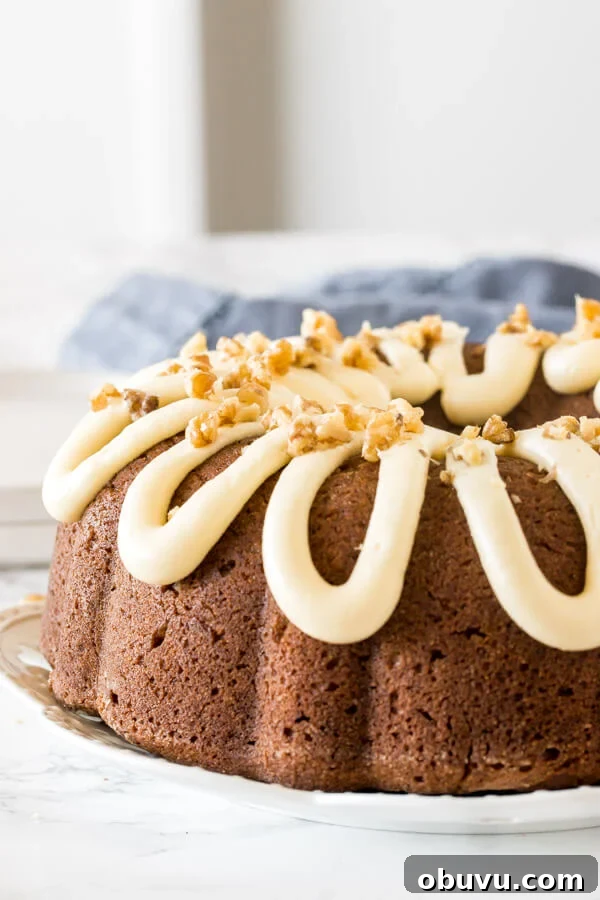 Moist banana bundt cake with a drizzle of thick cream cheese icing on top and sprinkled with walnuts.