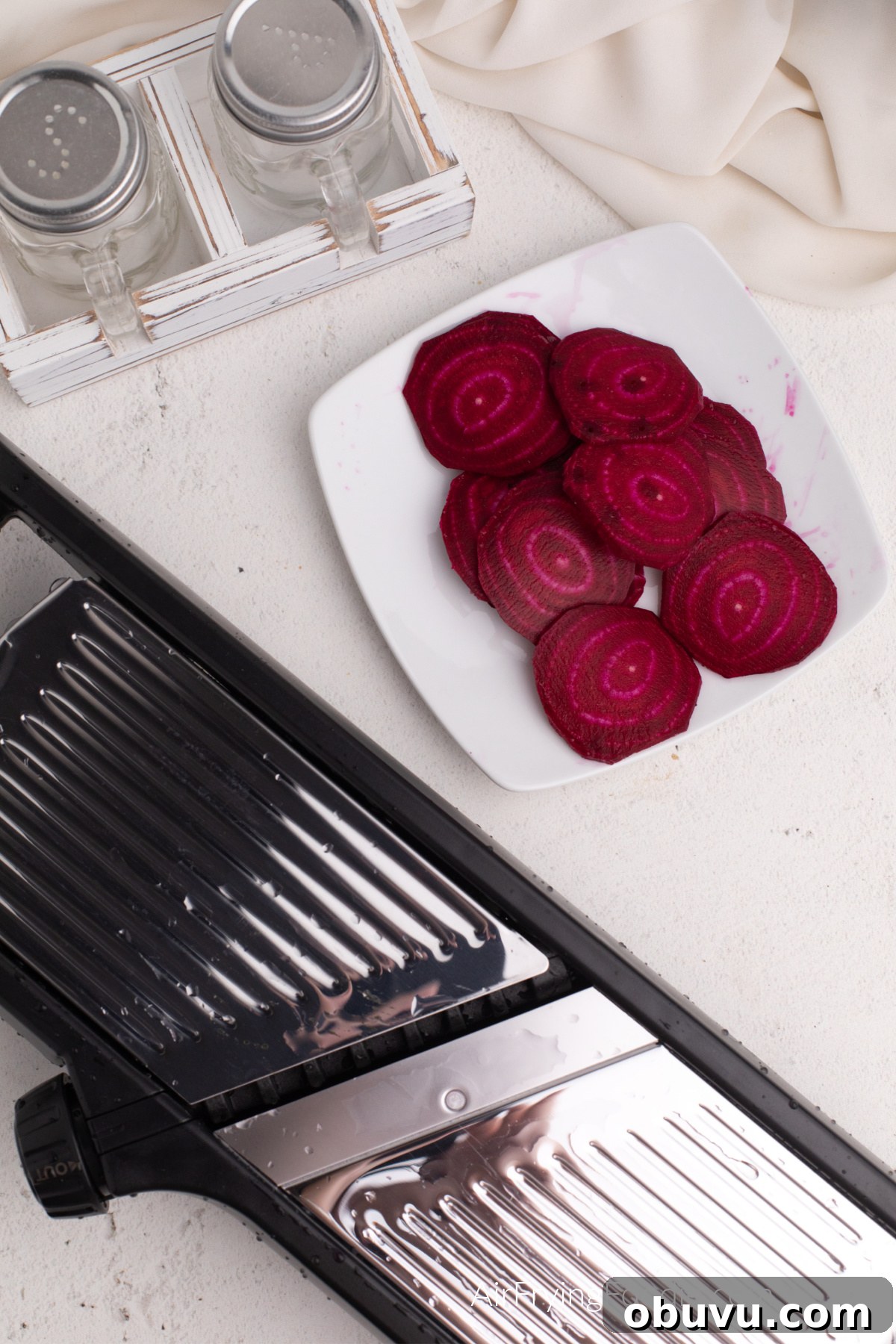 Crispy Air Fryer Beet Chips Recipe: Quick Homemade Snack 4 Beets cut on a white plate after being sliced with a mandolin.