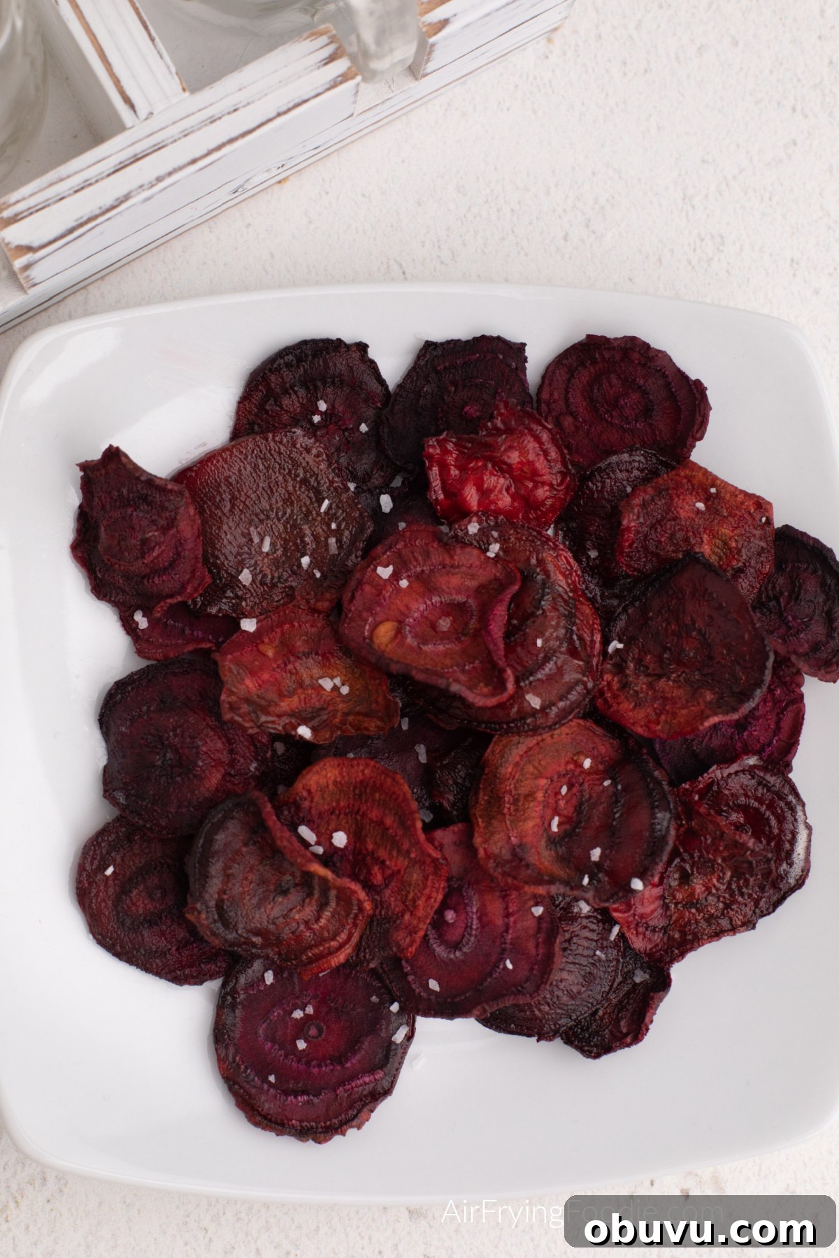 Crispy Air Fryer Beet Chips Recipe: Quick Homemade Snack 8 Air fryer beet chips on a white plate, topped with kosher salt before serving.