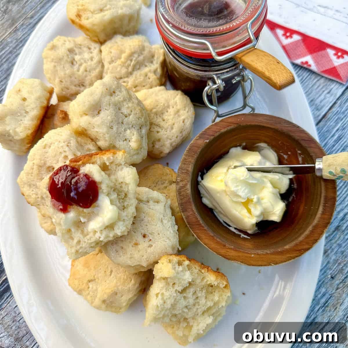 Flaky Buttermilk Biscuits Recipe for Perfect Homemade Biscuits 7 Baked biscuits on a plate with a bowl of butter and jar of jam.