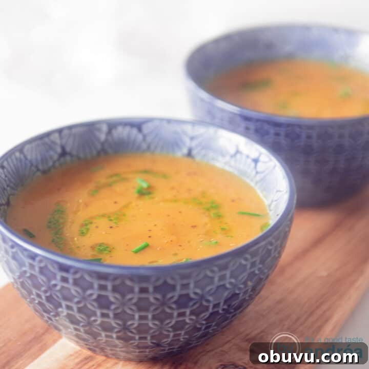 A square photo with two blue bowls filled with pumpkin soup with a delicious herbal dressing.