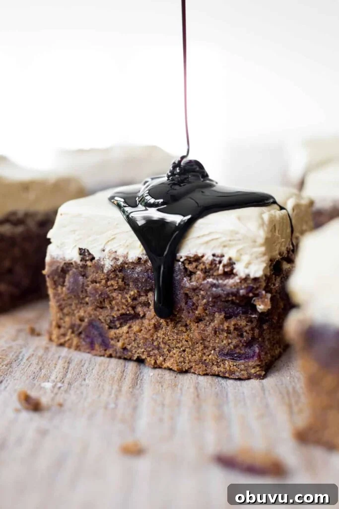A slice of Sticky Date Cake on a wooden board with a drizzle of black treacle.