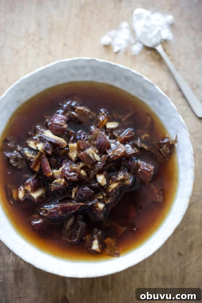 dates soaking in black tea in a white bowl