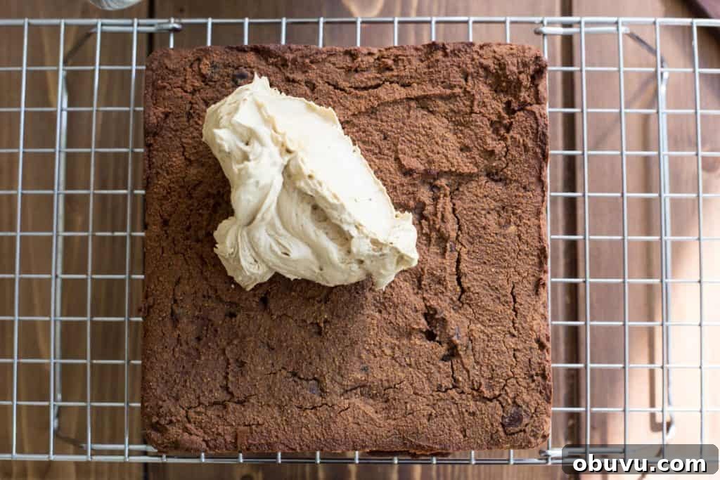 Sticky Date Cake on a cooling rack with buttercream on top
