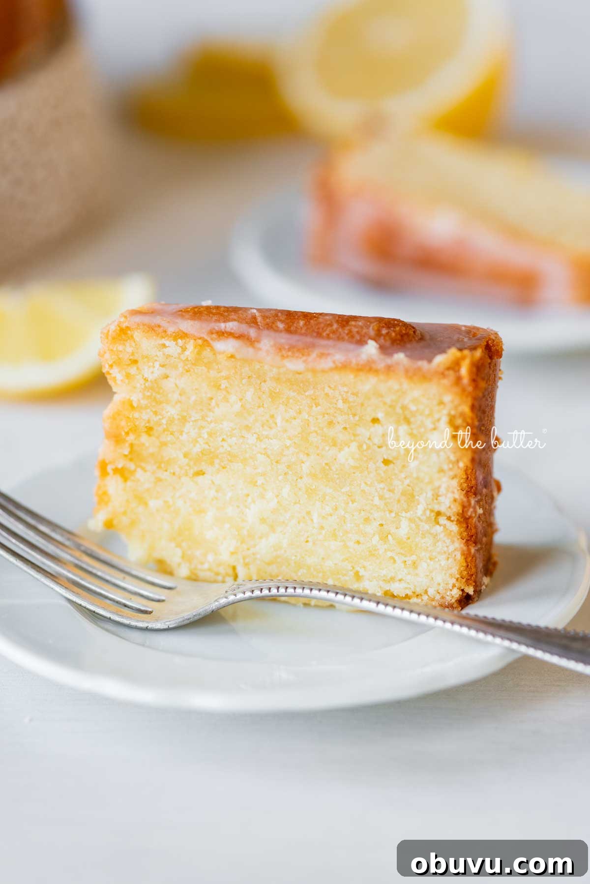 Lemon Cream Cheese Pound Cake Recipe with Zesty Glaze 6 Single slice of glazed lemon cream cheese pound cake on a white dessert plate