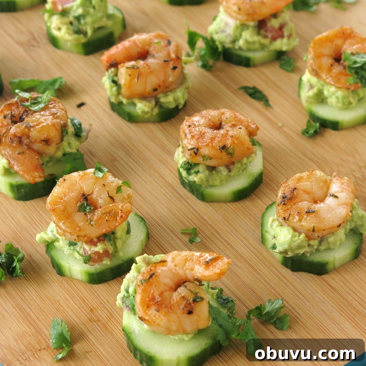Cajun Shrimp Guacamole Bites: Spicy Shrimp Appetizer Recipe 2 Cajun Shrimp Guacamole Bites on Cucumber rounds on serving board.