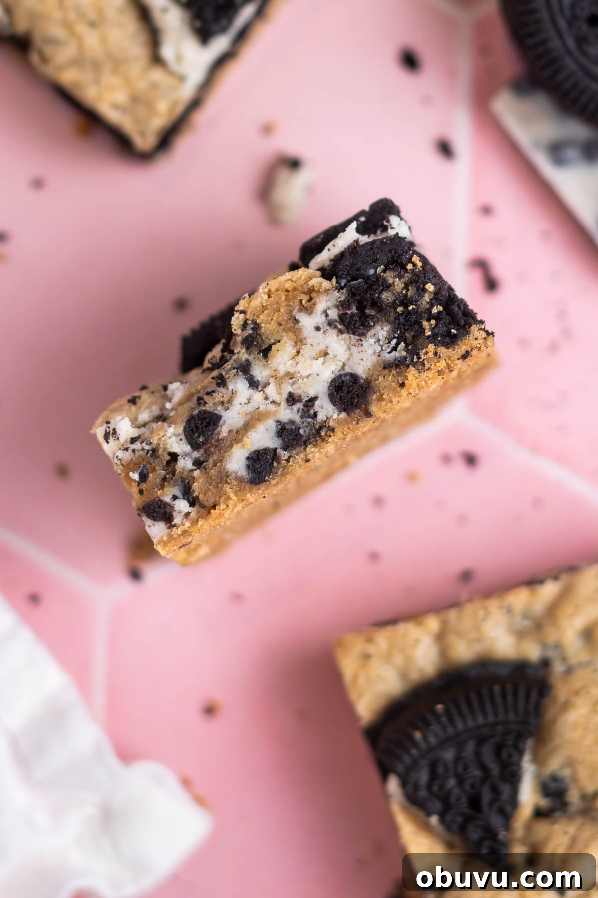 Soft Cookies and Cream Bars Recipe — Chewy & Irresistible 13 cookies and cream bar on it's side showing the layers of candy bars and cookies inside