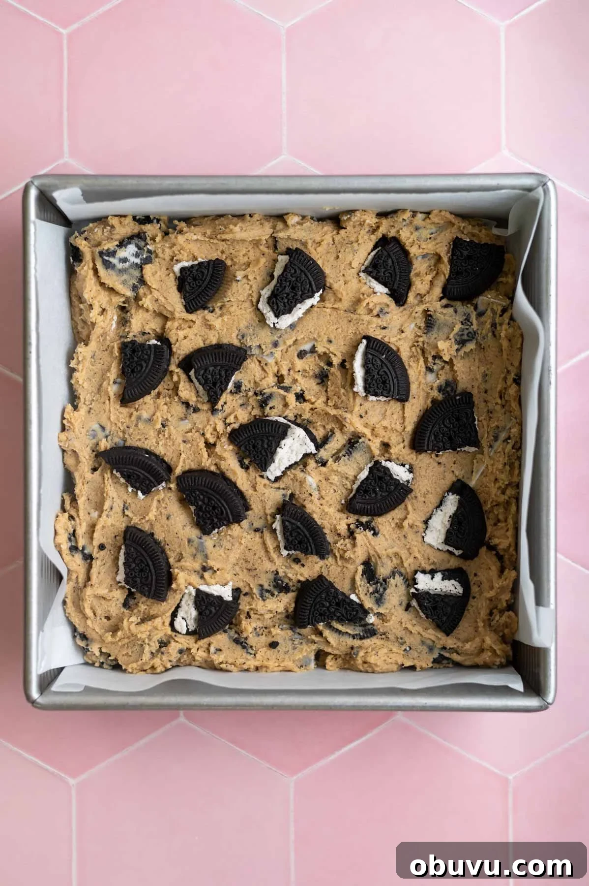 Soft Cookies and Cream Bars Recipe — Chewy & Irresistible 10 oreo cookies broken and pressed into the top of the bar cookie dough in a baking pan