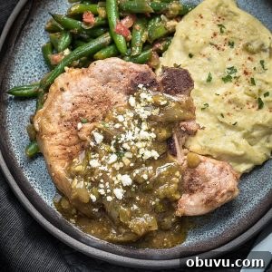 Garlic Butter Mushroom Pork Chops Without Canned Soup 6 Mexican pork chops with chile verde sauce and cotija cheese served with mexican green beans and tomatoes and cheesy cauliflower mash on a dark handmade plate.