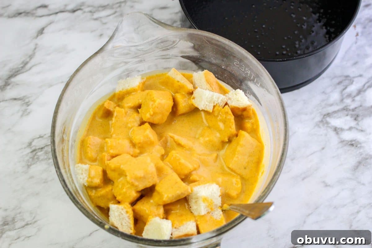 Instant Pot Pumpkin Bread Pudding with Air Fryer Crisp Option 5 A bowl filled with cubes of bread that are covered in a pumpkin bread pudding batter.