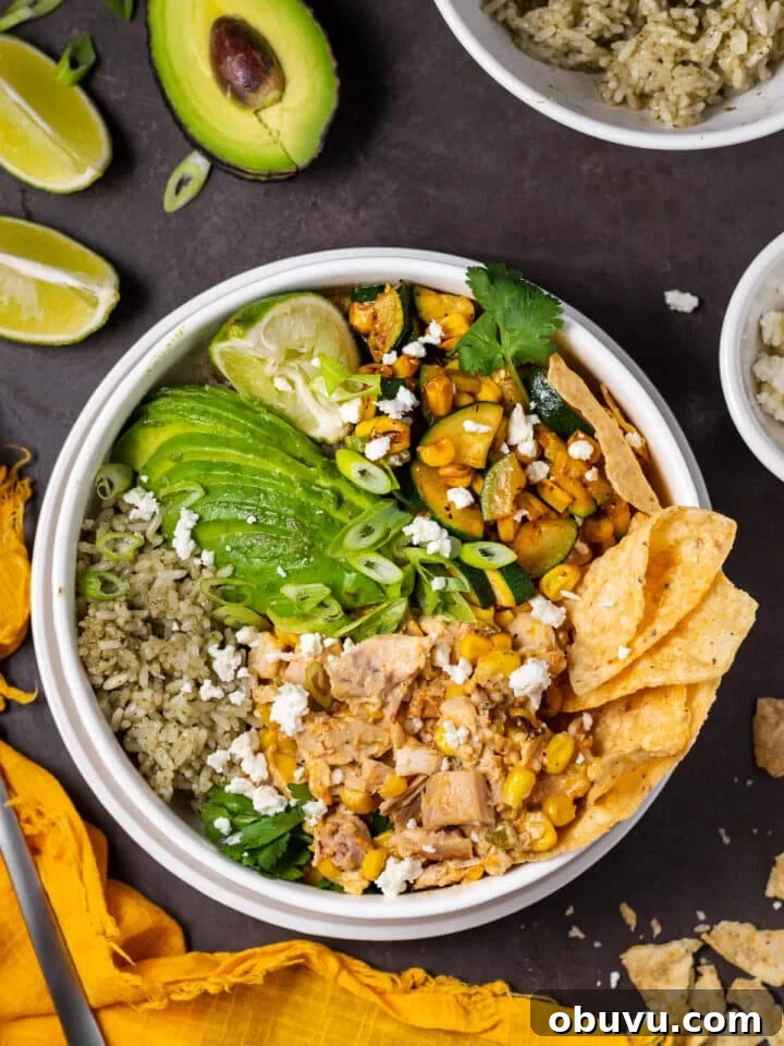 white bowl with cilantro lime rice, sliced avocado, mexican street corn chicken, zucchini and corn, tortilla chips and lime wedge