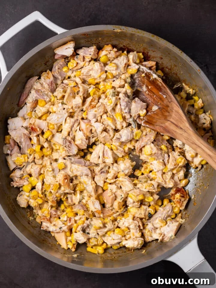 chicken, corn and street corn dip mixed together in a skillet