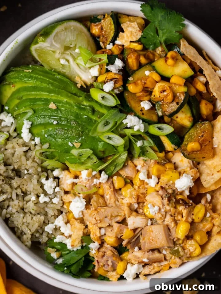 close up view of sliced avocado, cilantro lime rice, cooked zucchini and corn and creamy cubed chicken, feta, green onions
