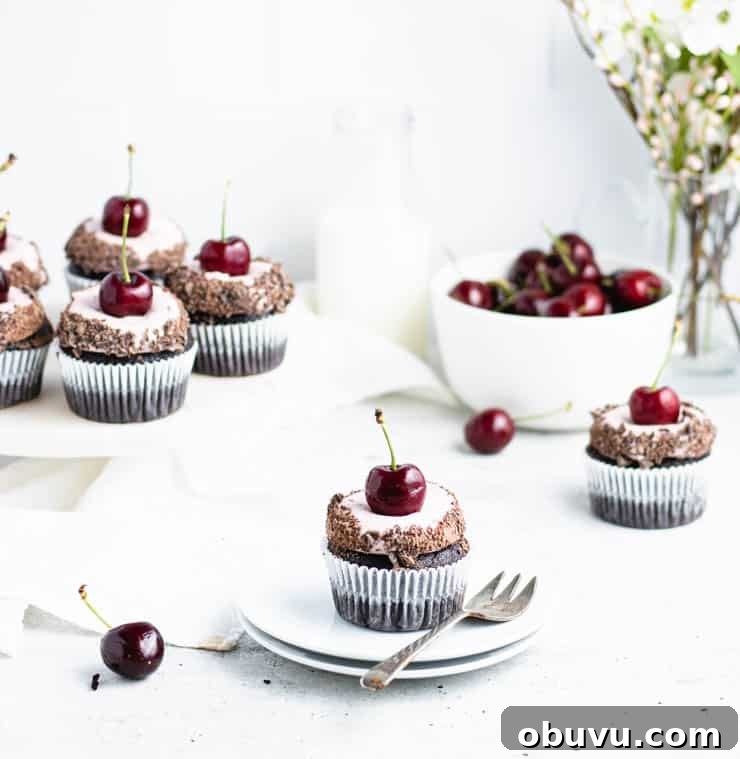 cupcake on a plate in front of a cake stand of cupcakes.