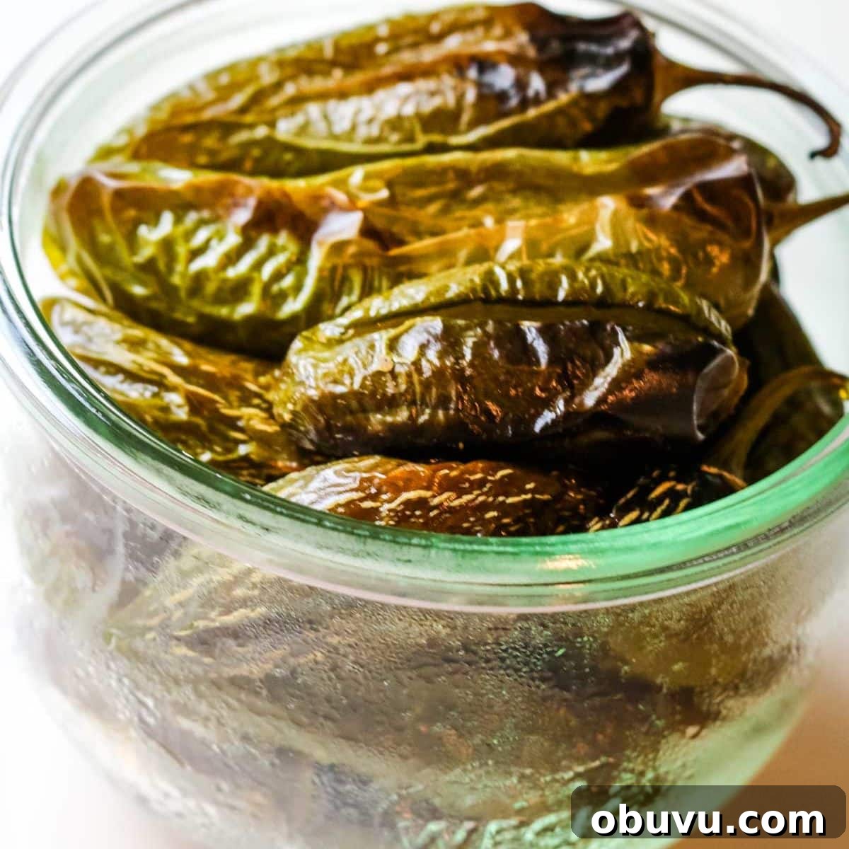 Charred Jalapeños: How to Roast and Use Smoky Peppers 5 roasted jalapenos in a glass bowl.