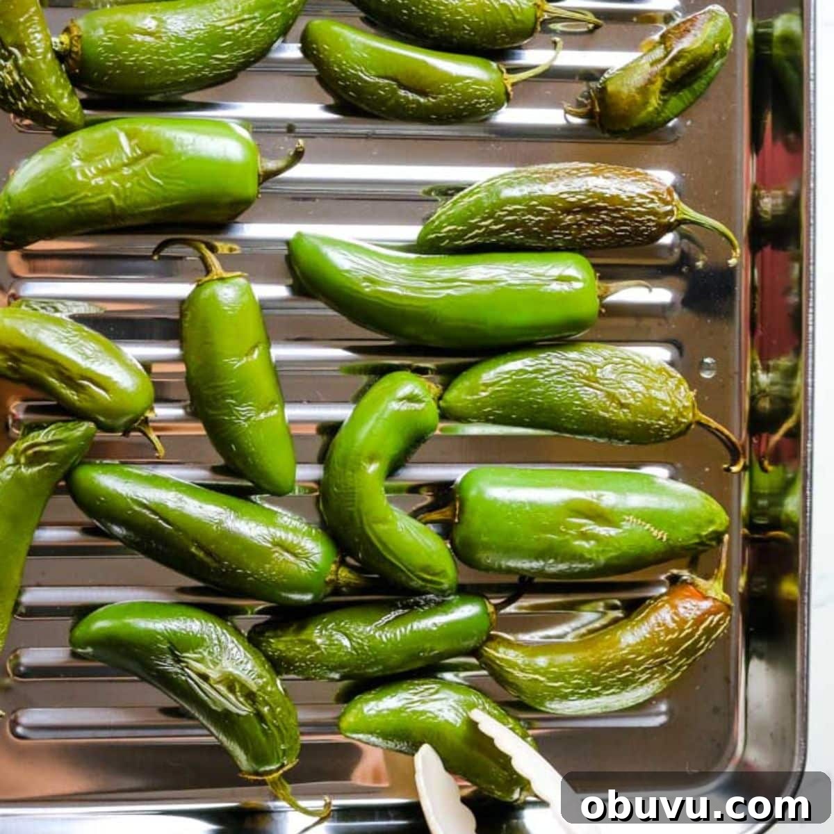 Charred Jalapeños: How to Roast and Use Smoky Peppers 7 roasted green jalapenos on a tray.
