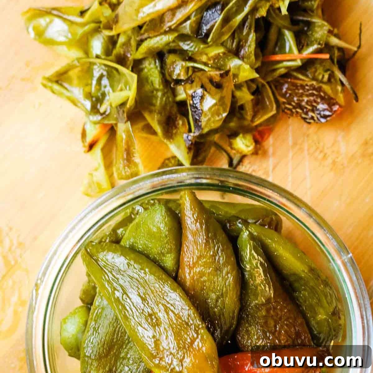 Charred Jalapeños: How to Roast and Use Smoky Peppers 9 peeled jalapenos in a glass bowl with its skin on the side.