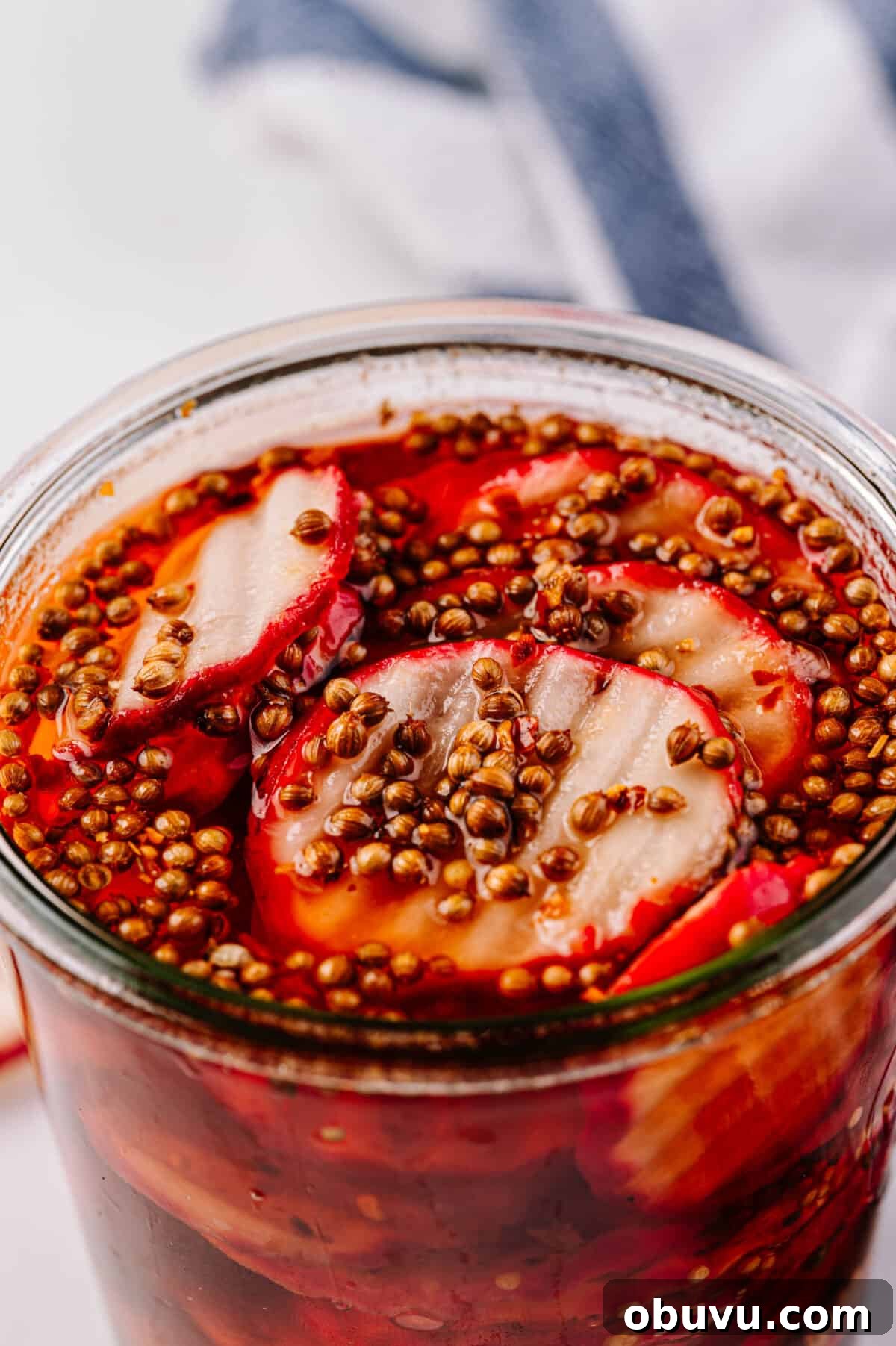 close up vertical shot of pickled radishes with radish coins in glass jar