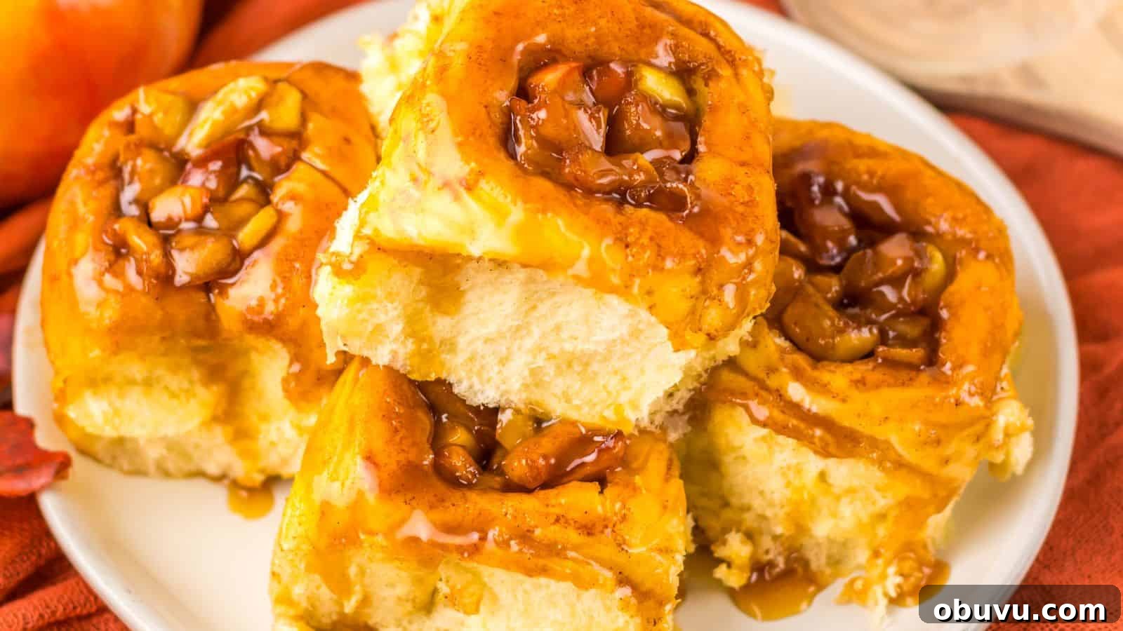 A plate of five sticky buns topped with caramelized nuts and sauce, resting on a red cloth.