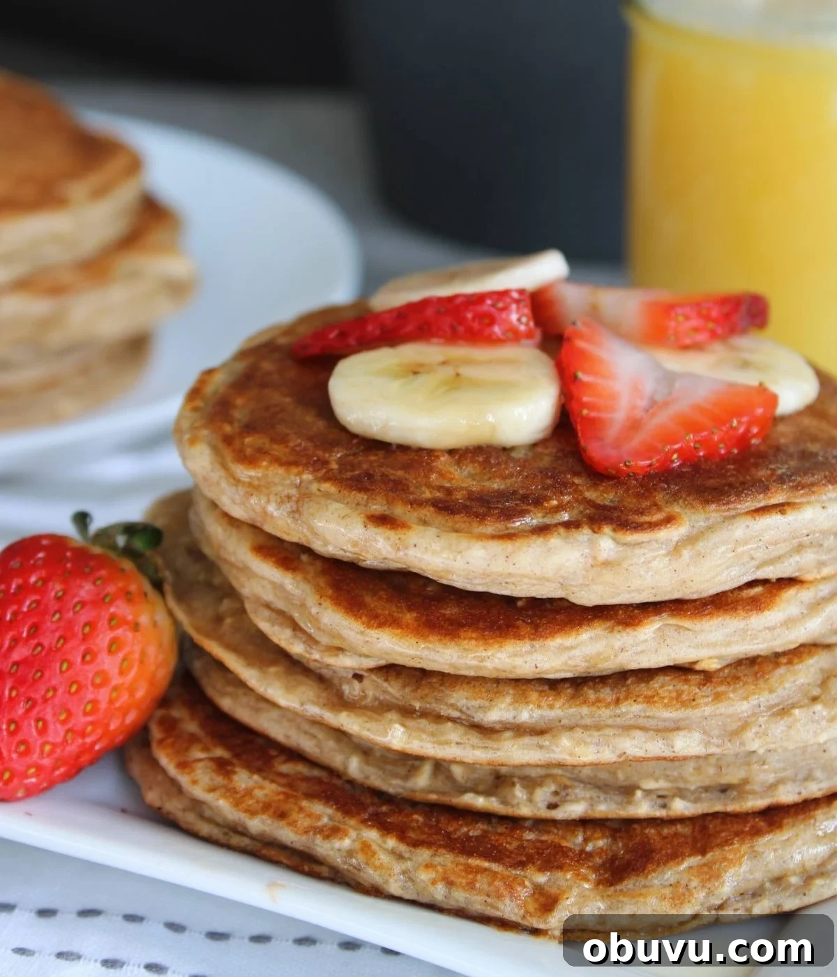 High-Protein Pancake Recipe for More Muscle and Energy 8 Stack of protein packed pancakes with pure maple syrup, strawberries, bananas, and a glass of orange juice.