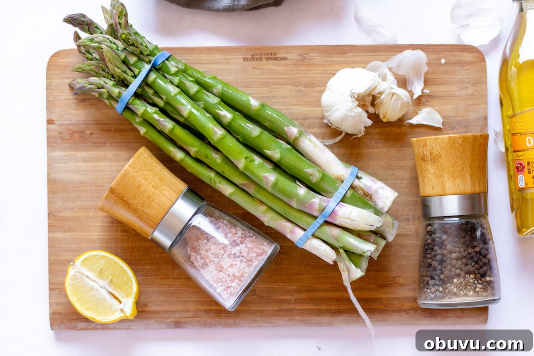 Images shows a bundle of asparagus on a cutting board with salt, pepper and lemon nearby.