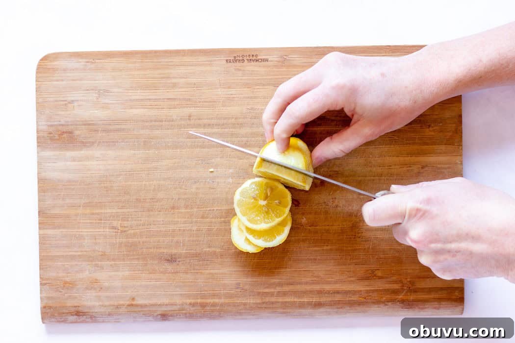 Image, taken from above, shows a hand slicing lemons