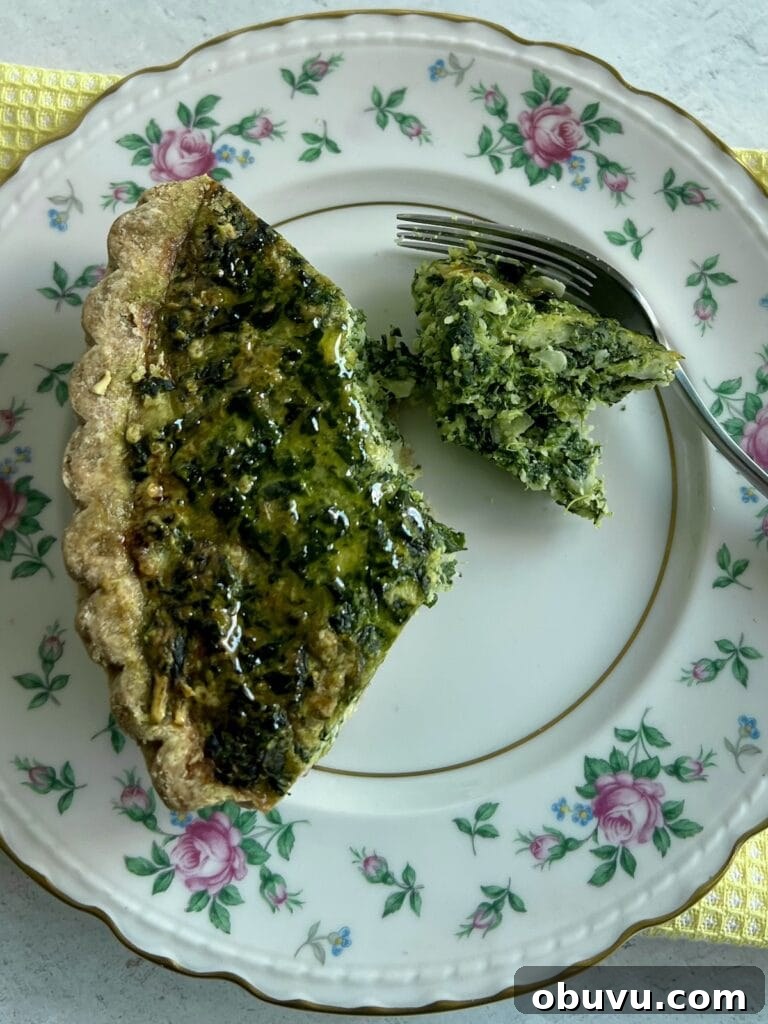 Spinach and Swiss Quiche with Frozen Pie Crust 11 Piece of spinach swiss quiche with frozen pie crust broken off of a slice with fork on plate.