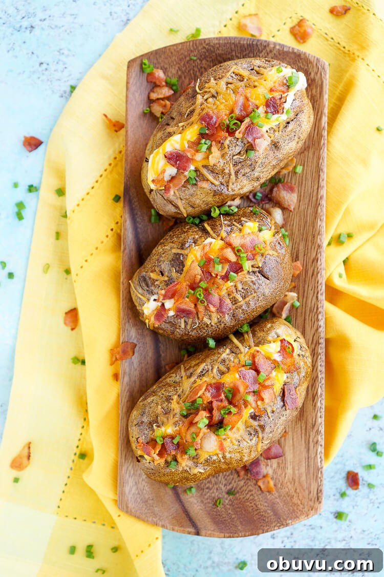 These are the Best Ever Baked Potatoes, they're perfectly seasoned and loaded up with a creamy dressing, cheddar cheese, bacon, and chives!