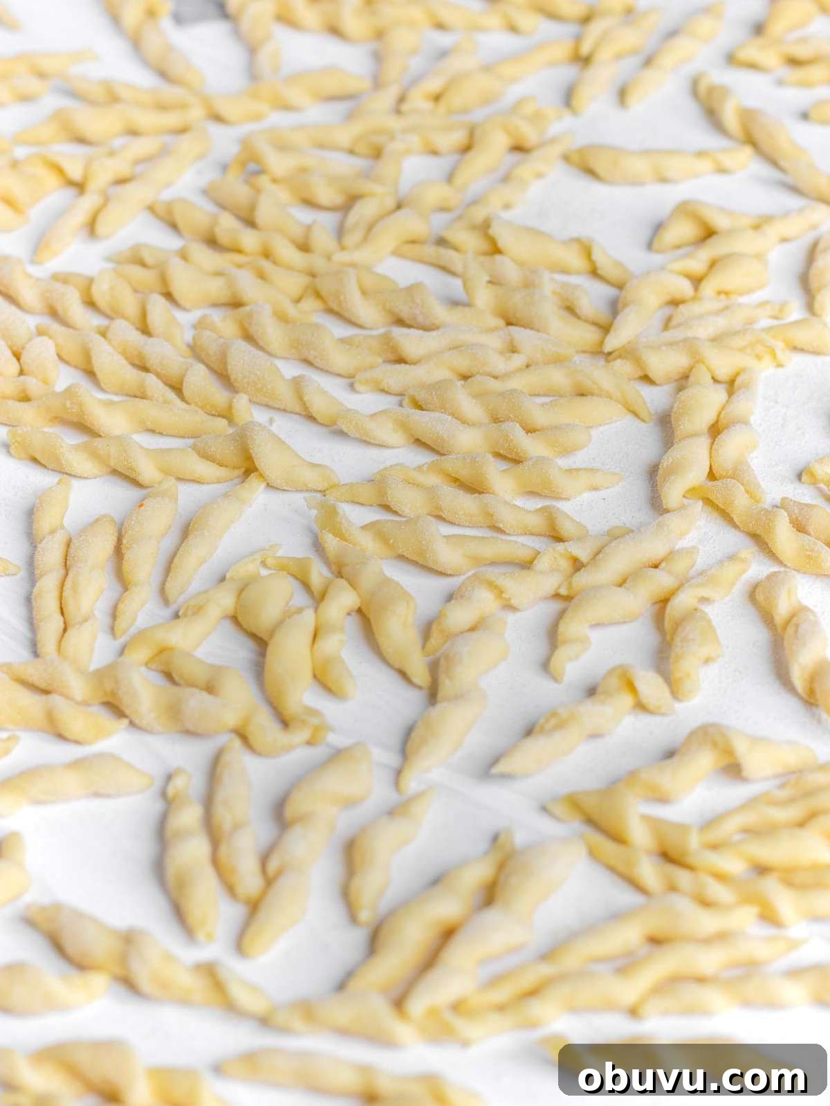 Handmade Trofie Pasta Recipe: Authentic Ligurian Method 3 Close up of homemade trofie pasta drying on a worktop.