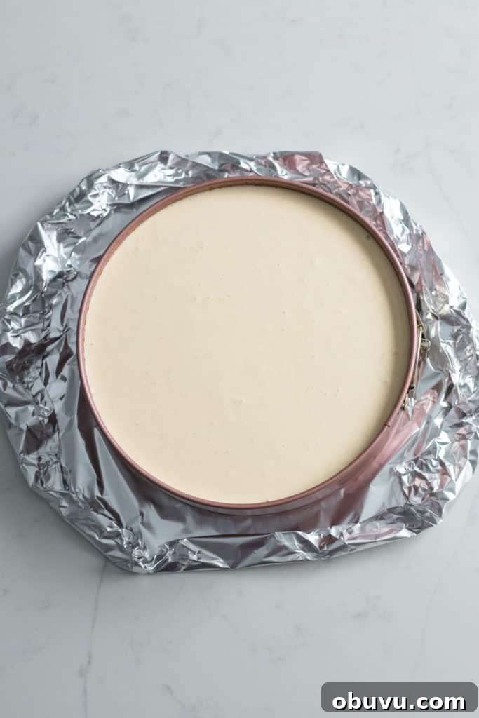 foil wrapped around pan of cheesecake batter