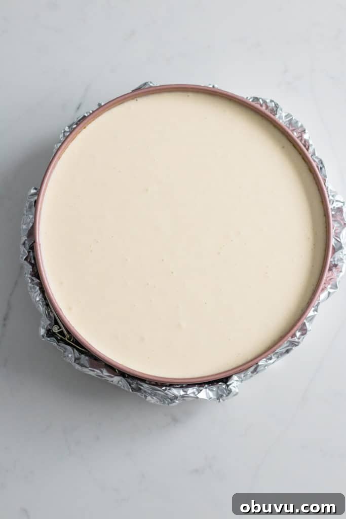 foil wrapped around pan of cheesecake batter