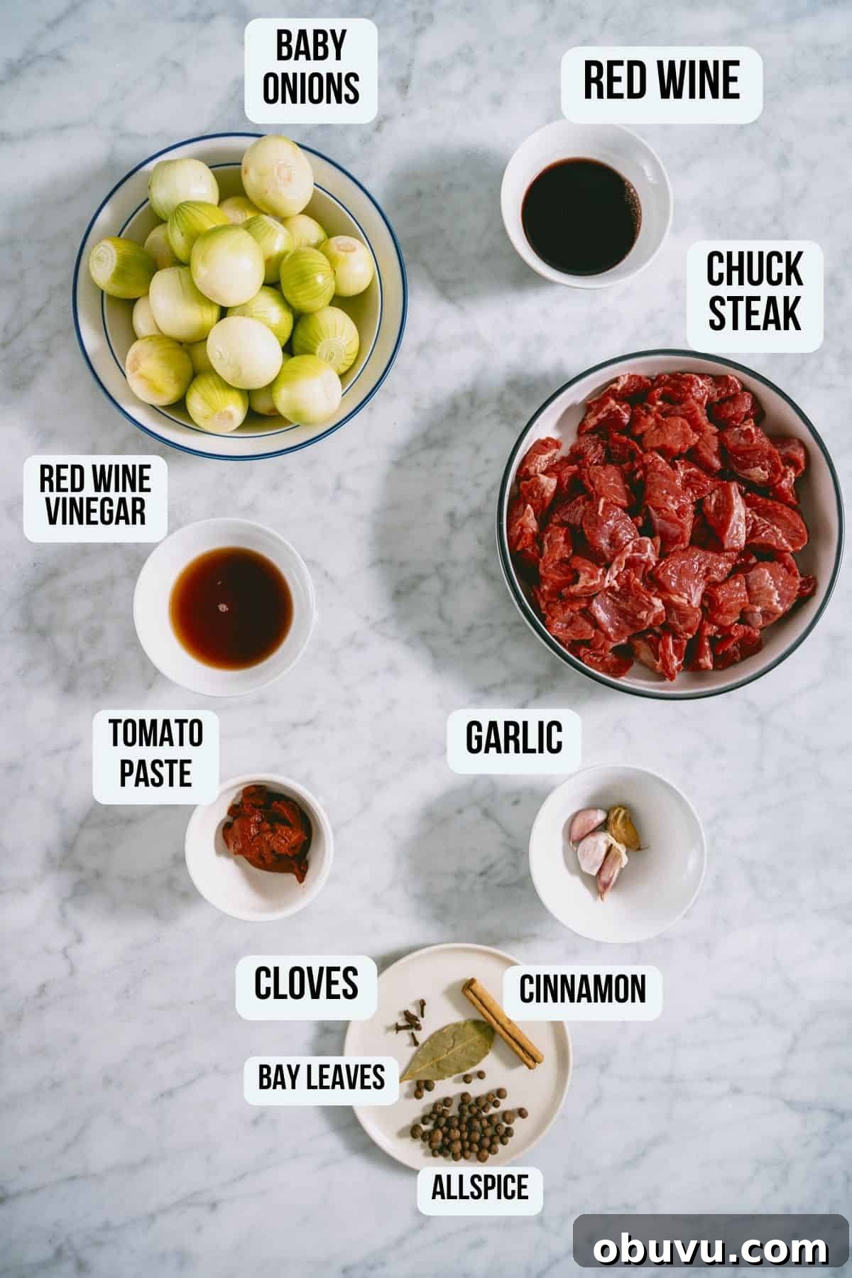 the ingredients to make beef stifado on a white marble table.
