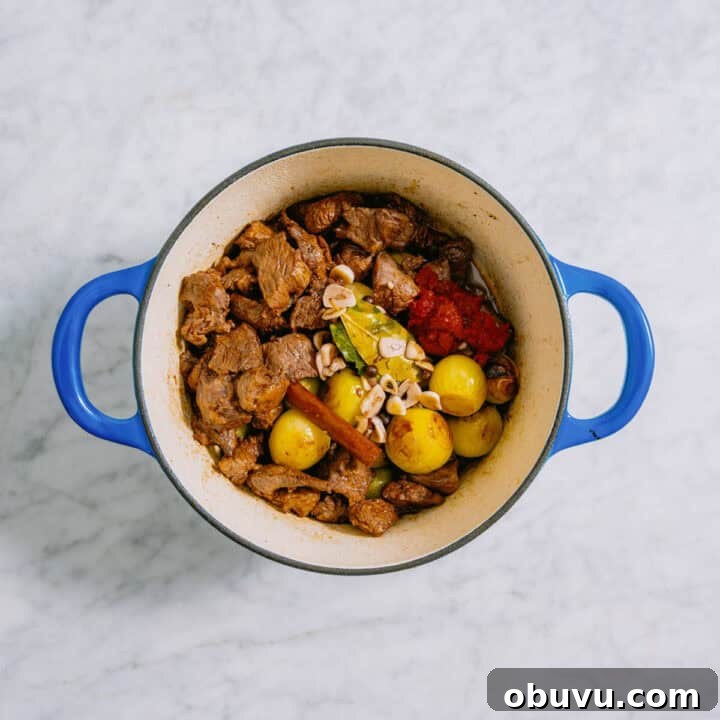 greek beef stew in a blue pot cooking.