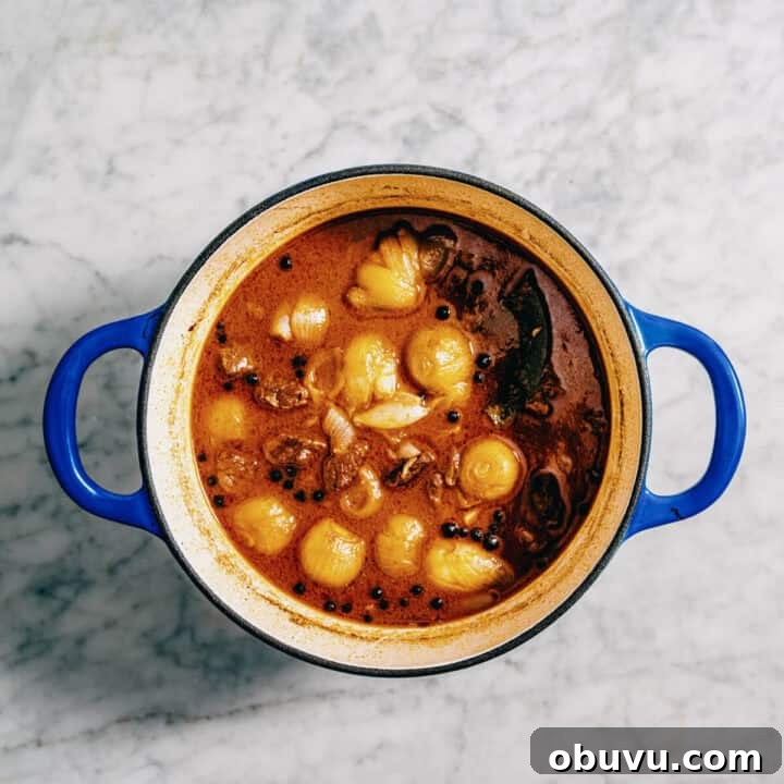 Greek beef stew finished and looking glossy and rich in a blue pot.