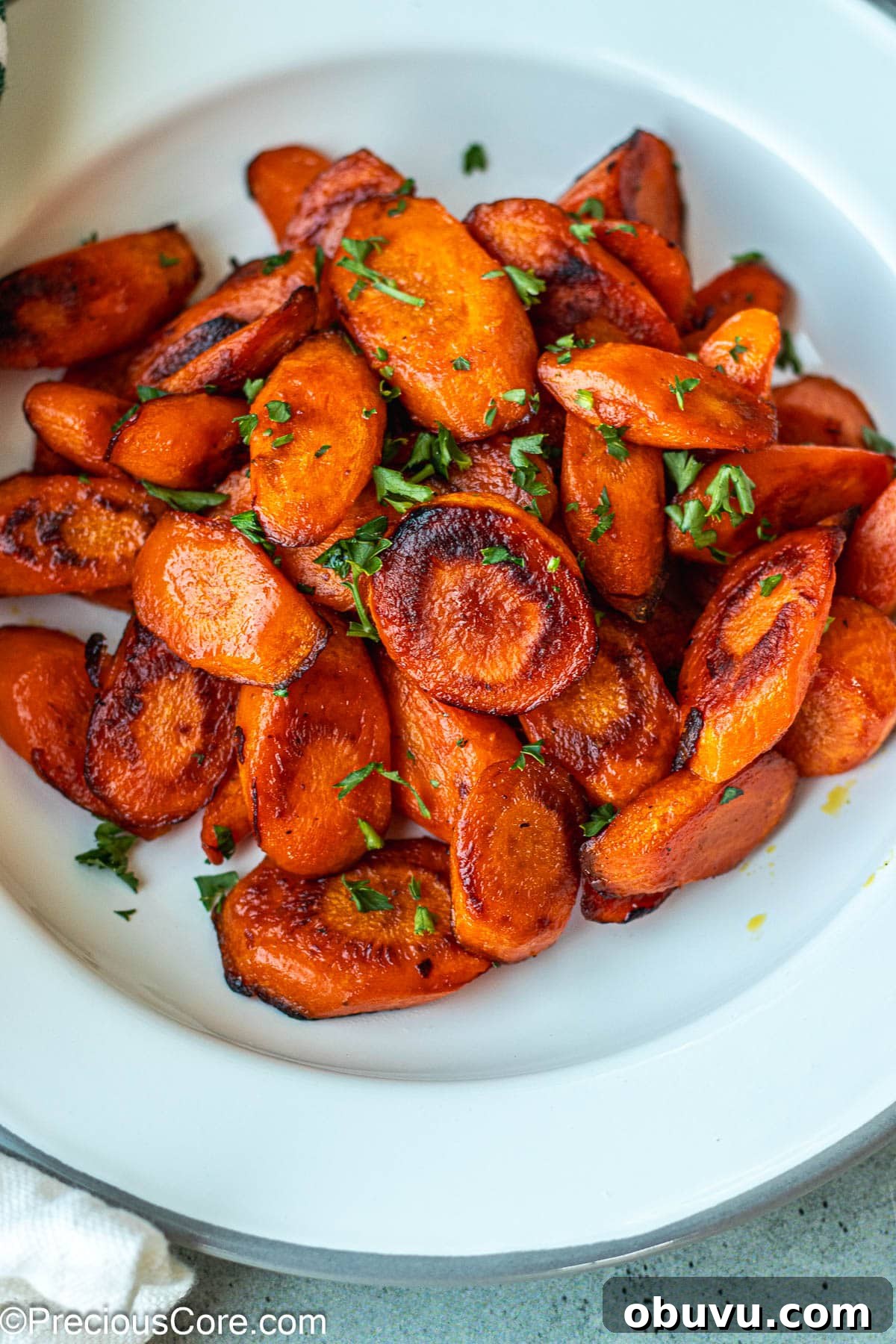 Crispy Pan-Fried Carrots with Garlic and Herbs 7 Carrots on a white plate garnished with parsley.