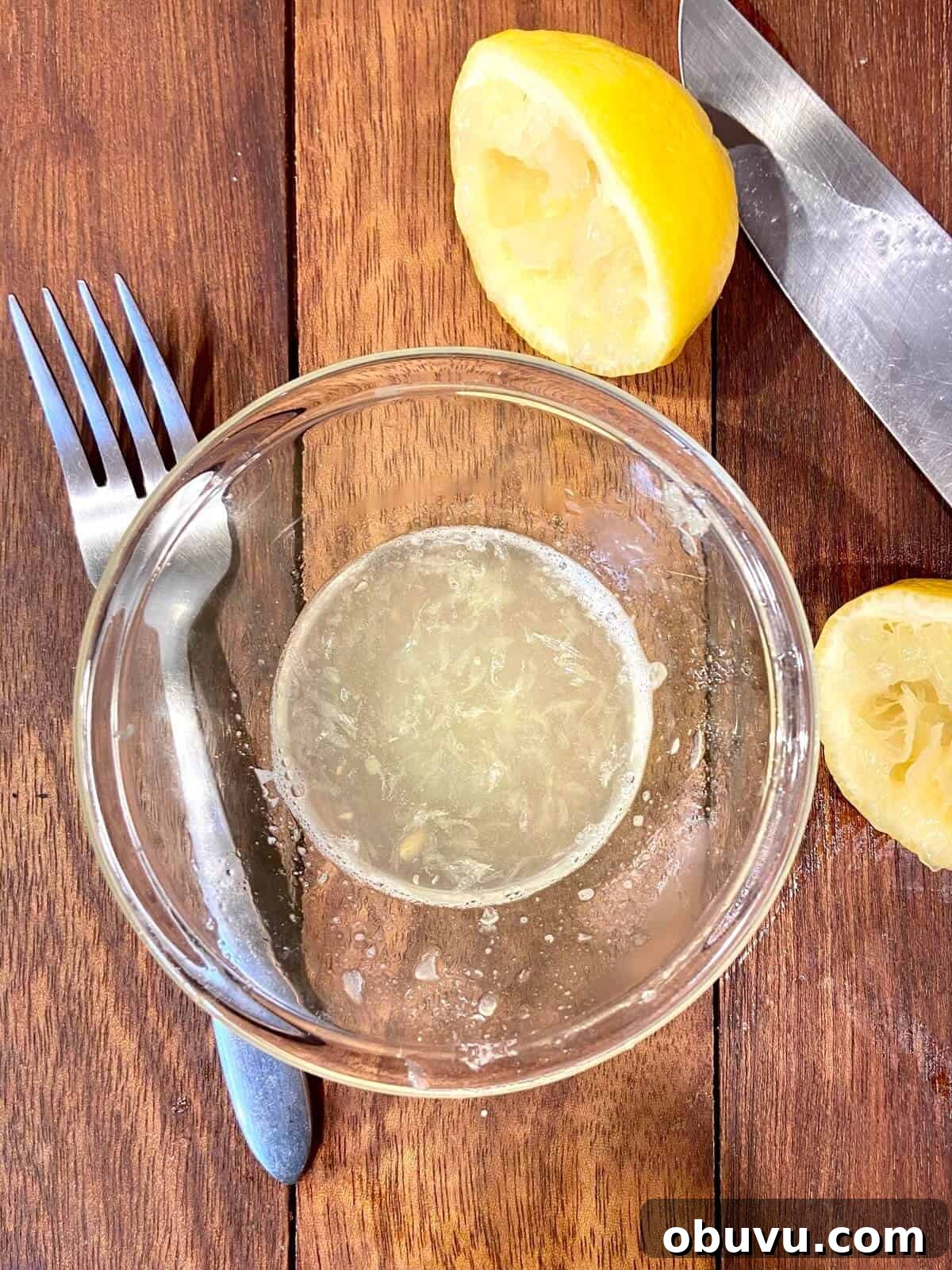 Lemon Scaloppine Recipe: Tender Veal in Zesty Lemon Sauce 7 Lemon juice squeezed into a small bowl, with fork and knife on table.
